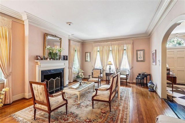 living room with hardwood / wood-style floors, a premium fireplace, crown molding, and a wealth of natural light