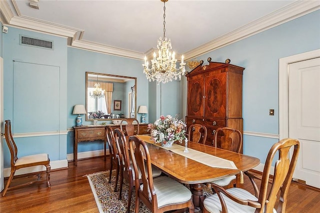 dining room featuring dark hardwood / wood-style floors, an inviting chandelier, and crown molding