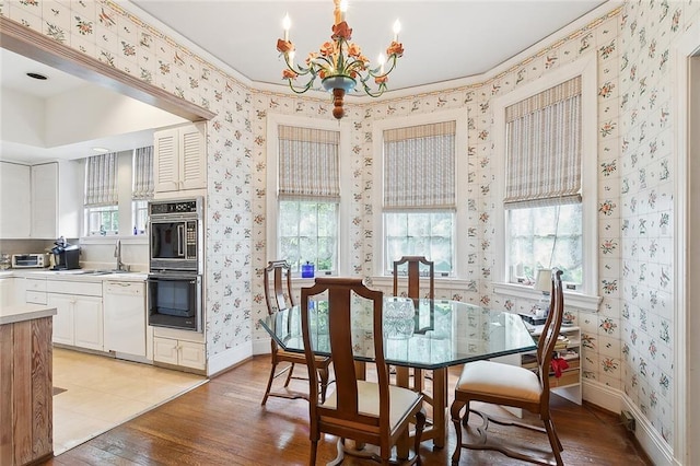 dining room featuring a notable chandelier, sink, light wood-type flooring, and crown molding