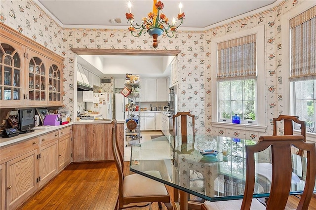 dining area with ornamental molding, a chandelier, and light hardwood / wood-style floors