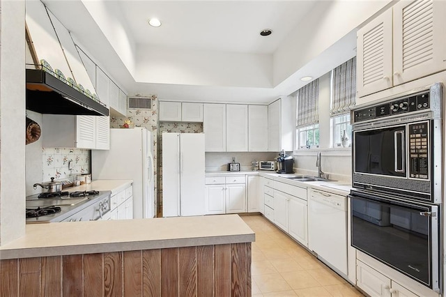 kitchen with backsplash, white appliances, a tray ceiling, sink, and white cabinets