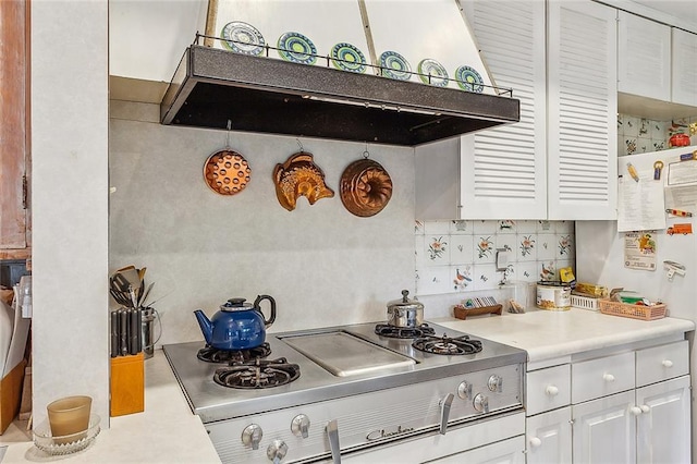 kitchen with stove, exhaust hood, white refrigerator, decorative backsplash, and white cabinetry