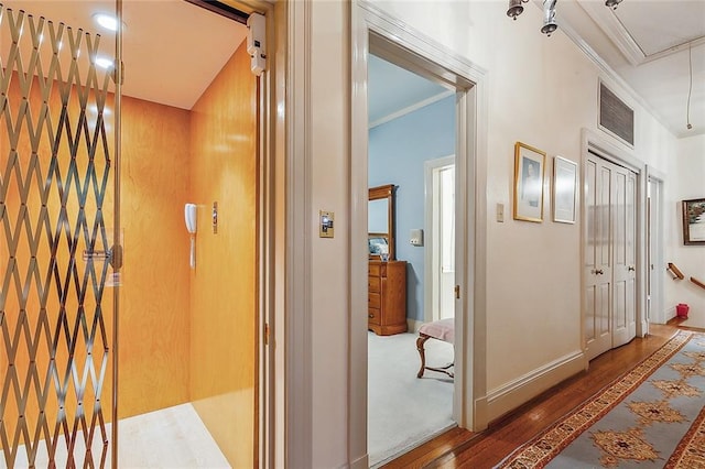 hall with dark hardwood / wood-style flooring, ornamental molding, and elevator