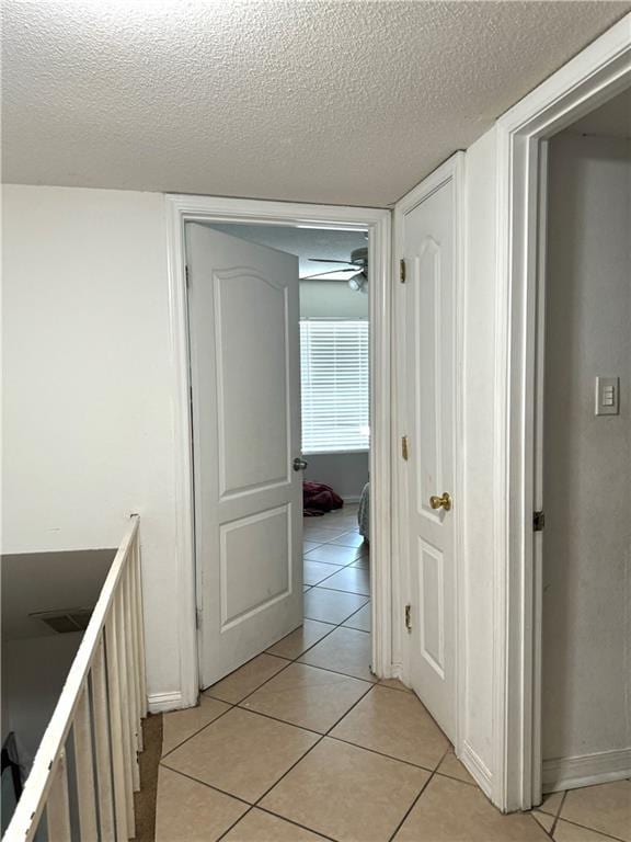 corridor featuring a textured ceiling and light tile patterned floors