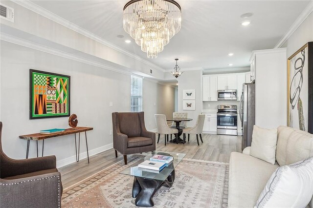 living room featuring crown molding, light hardwood / wood-style flooring, and a notable chandelier