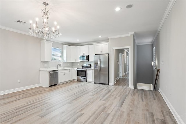 kitchen with appliances with stainless steel finishes, sink, pendant lighting, light wood-type flooring, and white cabinetry