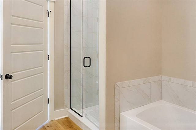 bathroom with hardwood / wood-style flooring and separate shower and tub