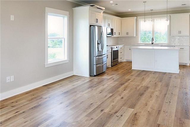 kitchen with plenty of natural light, decorative backsplash, appliances with stainless steel finishes, and light hardwood / wood-style floors