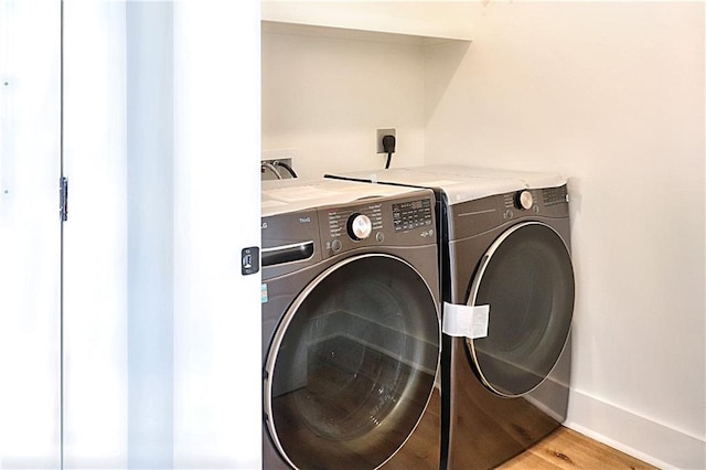 clothes washing area featuring light hardwood / wood-style flooring and washer and dryer