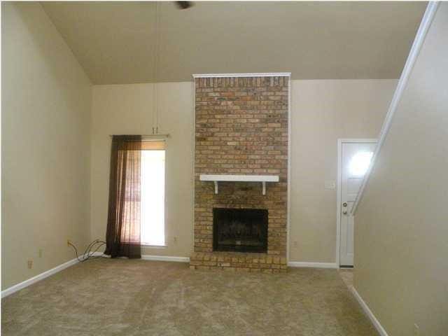 unfurnished living room featuring a brick fireplace, carpet, and vaulted ceiling