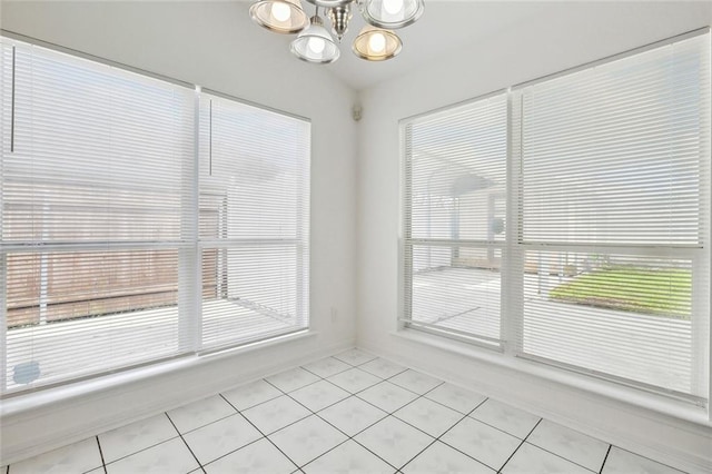 unfurnished dining area featuring light tile patterned flooring and an inviting chandelier