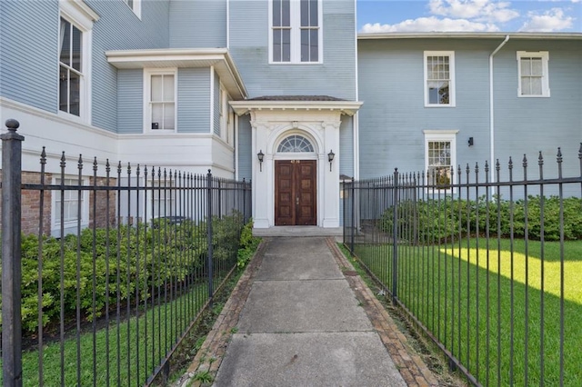 entrance to property featuring a lawn and fence