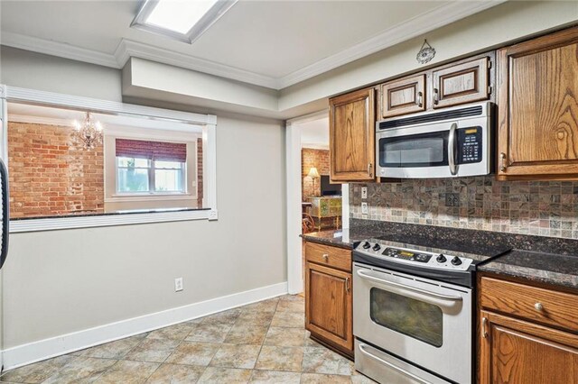 kitchen featuring appliances with stainless steel finishes, dark stone counters, and crown molding