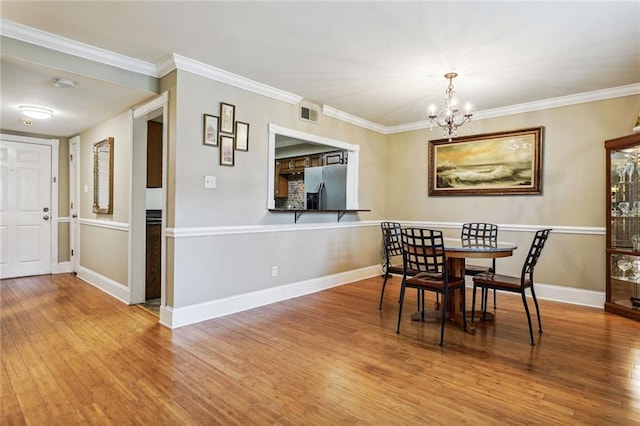 dining area featuring a notable chandelier, visible vents, ornamental molding, and wood finished floors