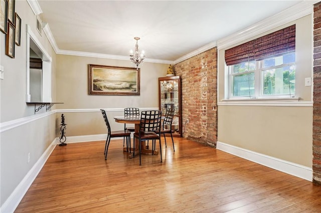 dining room with baseboards, visible vents, ornamental molding, wood finished floors, and a notable chandelier