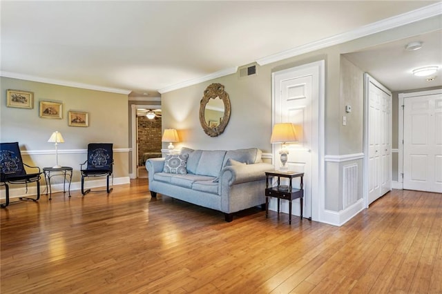 living room featuring baseboards, wood finished floors, visible vents, and crown molding