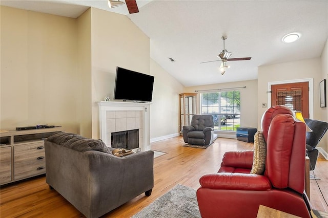 living room featuring light hardwood / wood-style flooring, lofted ceiling, ceiling fan, and a tile fireplace