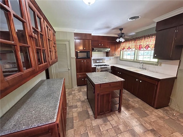 kitchen featuring backsplash, sink, gas range, a kitchen island, and black microwave