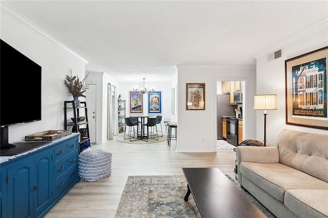 living room featuring ornamental molding, a notable chandelier, and light hardwood / wood-style flooring