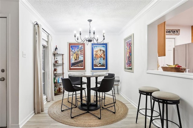 dining area featuring light wood-type flooring, a textured ceiling, and an inviting chandelier