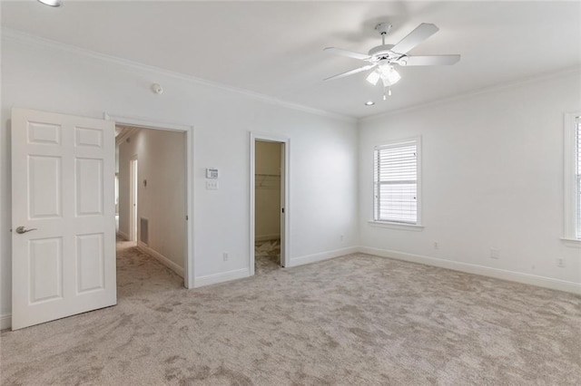 unfurnished bedroom with a walk in closet, ceiling fan, light carpet, and ornamental molding