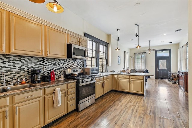 kitchen featuring light hardwood / wood-style floors, kitchen peninsula, hanging light fixtures, stainless steel appliances, and ceiling fan