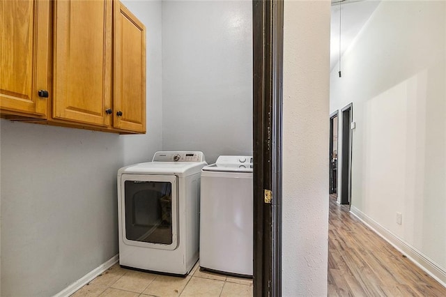 laundry area with separate washer and dryer, light hardwood / wood-style flooring, and cabinets