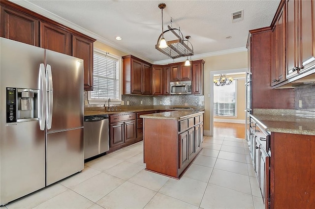 kitchen featuring crown molding, light stone counters, appliances with stainless steel finishes, and decorative backsplash