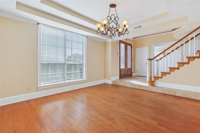 foyer entrance featuring light hardwood / wood-style floors, a chandelier, crown molding, and a tray ceiling