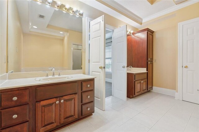 bathroom with tile patterned floors, crown molding, a raised ceiling, and dual bowl vanity