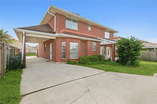 back of property with a carport and a yard