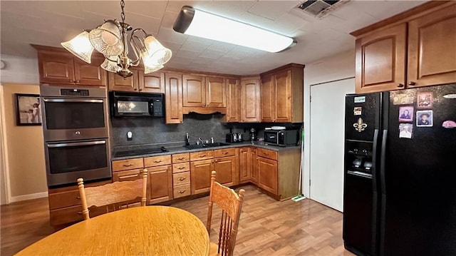 kitchen with backsplash, light wood-type flooring, black appliances, sink, and a notable chandelier