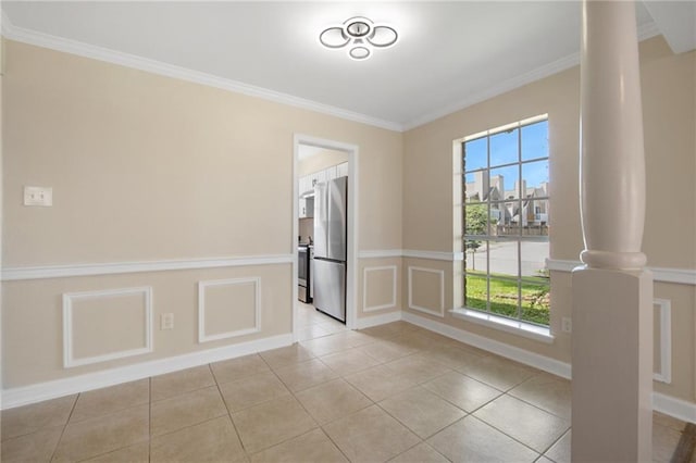 tiled spare room with decorative columns and crown molding