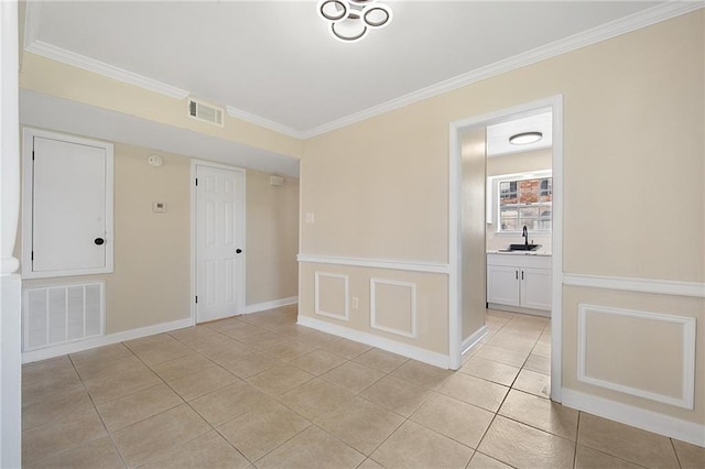 tiled empty room featuring sink and crown molding