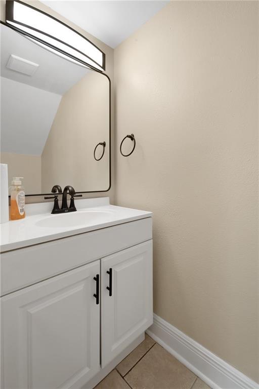 33 Brandon Hall Dr Unit A, Destrehan, LA 70047 - bathroom featuring vanity, baseboards, tile patterned flooring, and vaulted ceiling