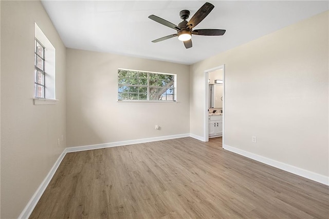 unfurnished bedroom featuring light wood-type flooring, ensuite bath, and ceiling fan