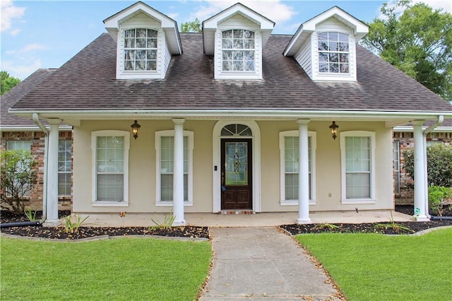 view of front of house with a front lawn, covered porch, roof with shingles, and stucco siding