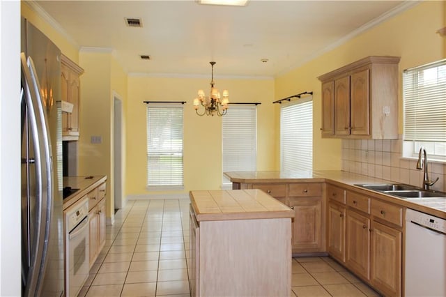 kitchen with light tile patterned flooring, light brown cabinetry, tile counters, a kitchen island, and white appliances