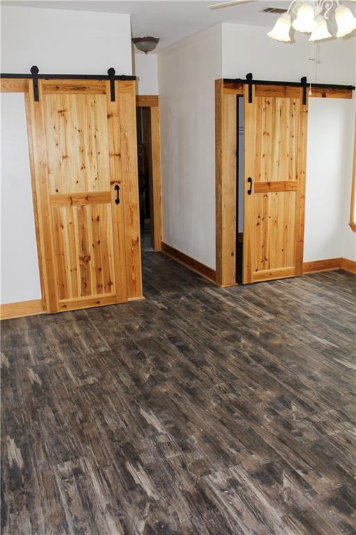 spare room with dark wood-type flooring, a barn door, and ceiling fan