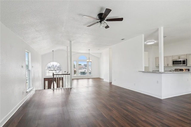 unfurnished living room featuring vaulted ceiling, a textured ceiling, ceiling fan with notable chandelier, and dark hardwood / wood-style floors