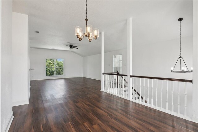 empty room featuring dark hardwood / wood-style flooring, lofted ceiling, and ceiling fan with notable chandelier