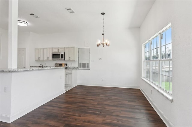 kitchen featuring appliances with stainless steel finishes, decorative light fixtures, dark hardwood / wood-style flooring, a chandelier, and light stone counters