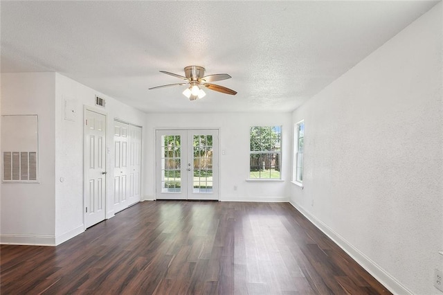 empty room with ceiling fan, a textured ceiling, dark hardwood / wood-style flooring, and french doors