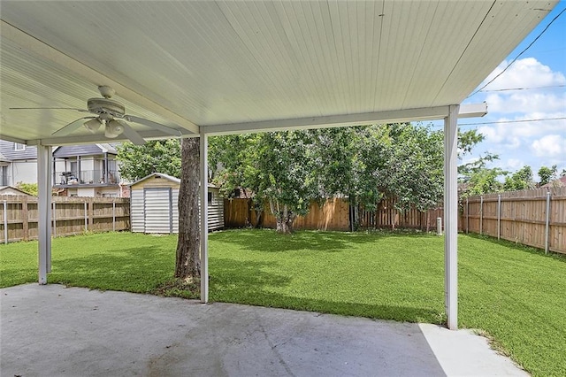 view of yard with ceiling fan, a storage shed, and a patio