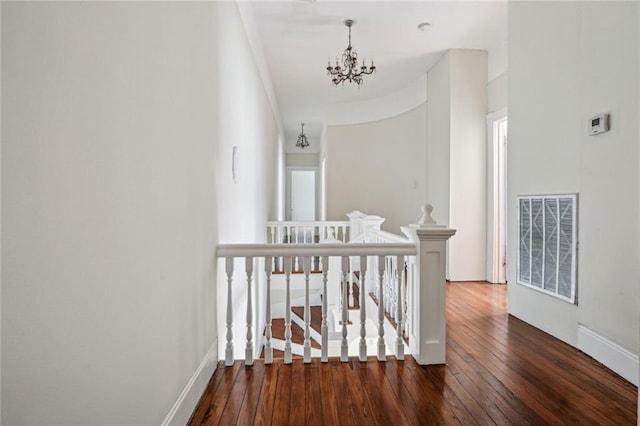 corridor with a notable chandelier, dark hardwood / wood-style flooring, and ornamental molding