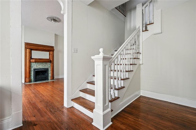 staircase with dark hardwood / wood-style flooring and a fireplace