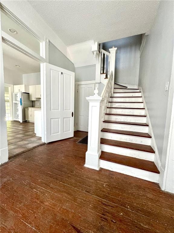 staircase with dark hardwood / wood-style flooring and a textured ceiling