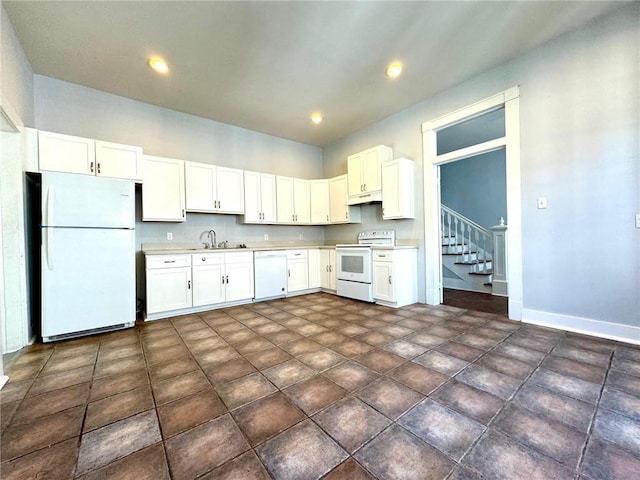 kitchen with sink, white cabinetry, dark tile patterned floors, and white appliances