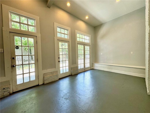 entryway featuring beamed ceiling, a healthy amount of sunlight, and a high ceiling