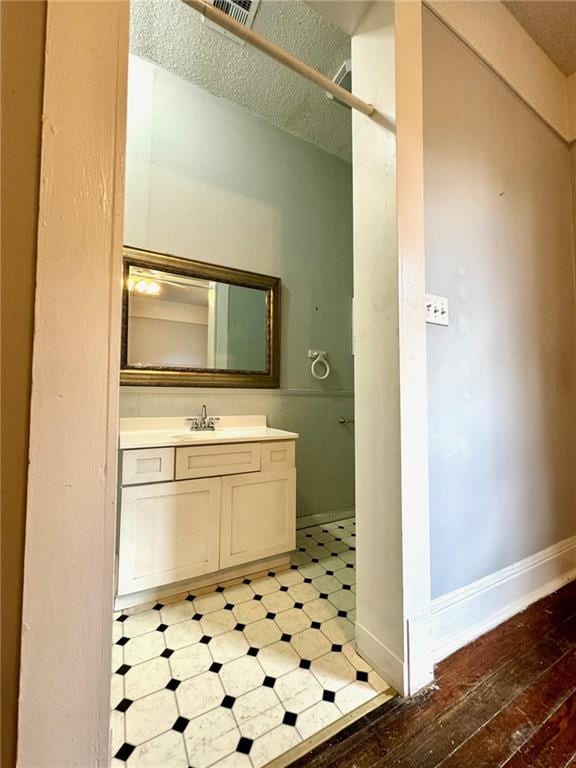 bathroom with hardwood / wood-style floors, vanity, and a textured ceiling